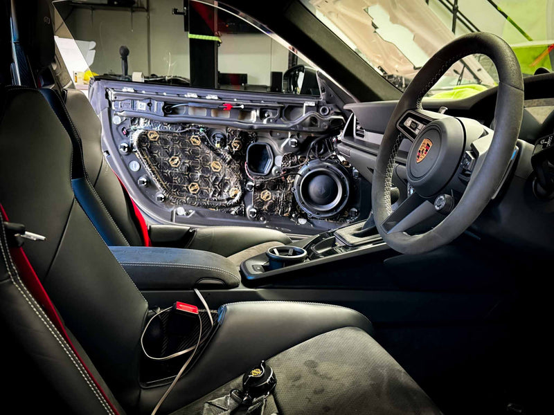 Soundproofing applied to Porsche GT3 door panel with technician working