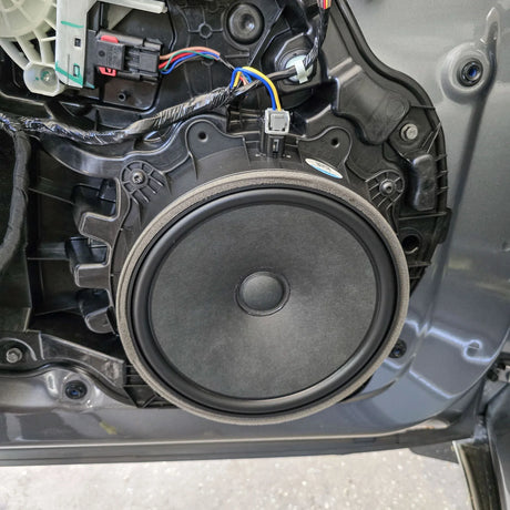 Factory Tesla Model Y RWD front door woofer shown in its original mounting position before the HELIX Ci3 upgrade